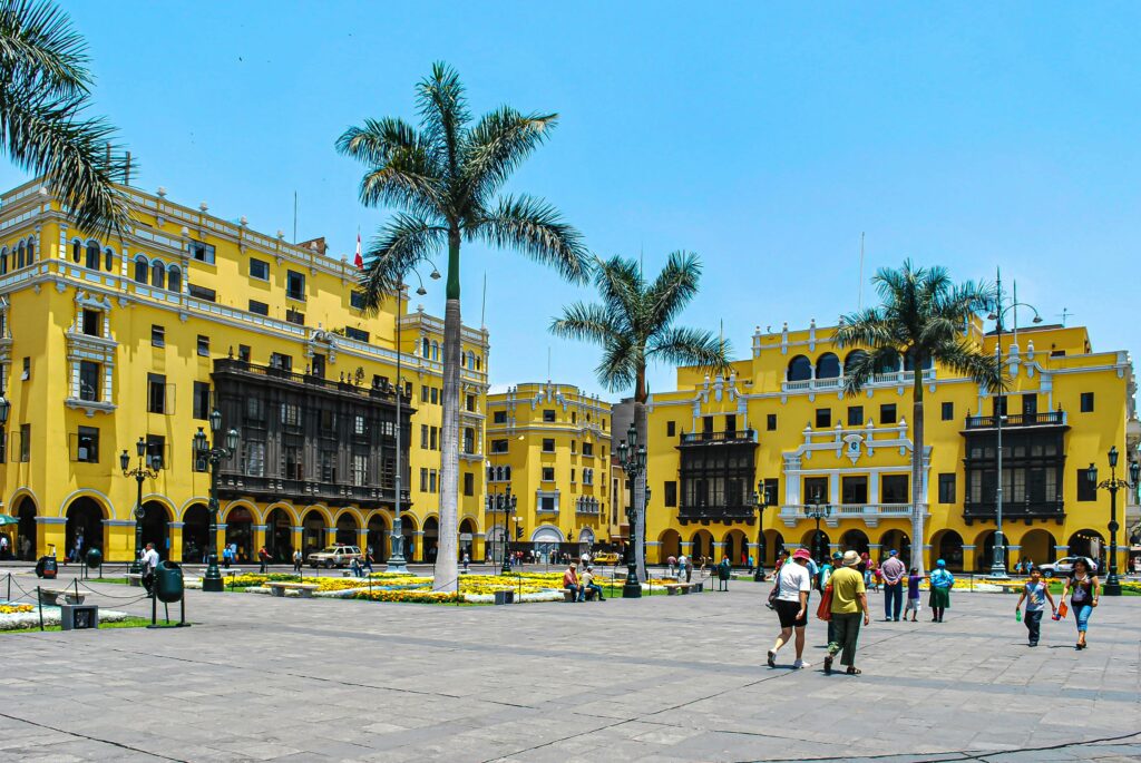Bustling day at Plaza Mayor showcasing vibrant colonial architecture and palm trees in Lima, Peru.